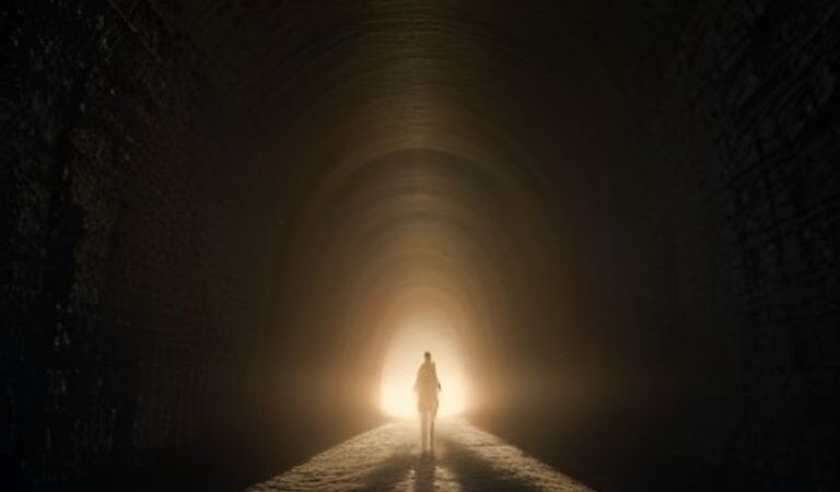 A Lone Soul Walks Toward the Light at Tunnel’s End